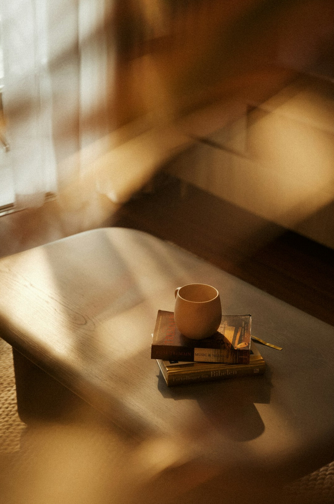 Books on a table beside a cup in warm light